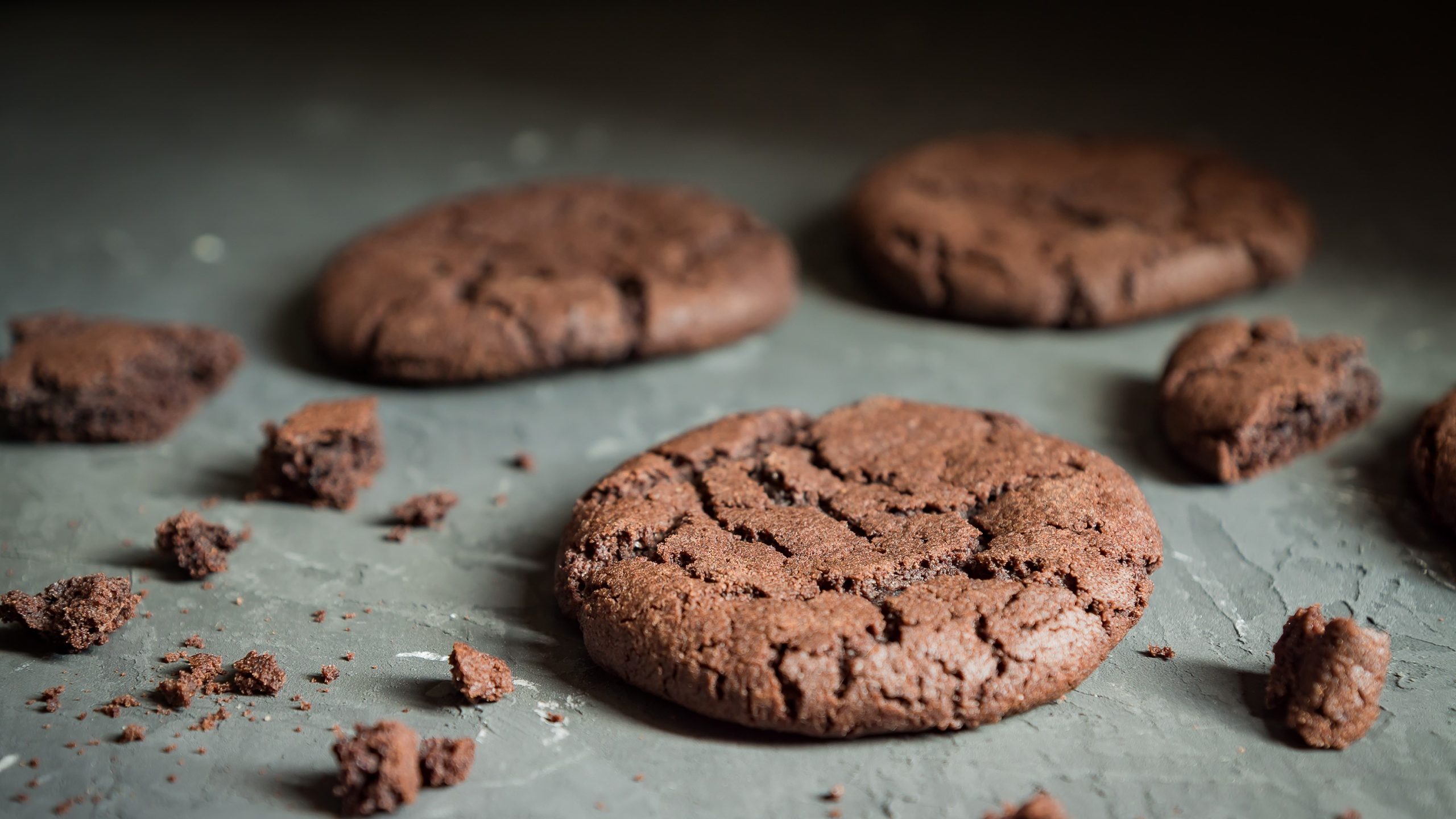 Mehrere Brownie Cookies auf einem grauen Tisch von der Seite fotografiert.