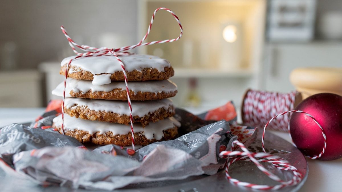 Frontalsicht: mehrere Nürnberger Lebkuchen liegen aufeinander und werden von einem weihnachtlich anmutendem Faden zusammengehalten. Die Anmutung ist weihnachtlich.