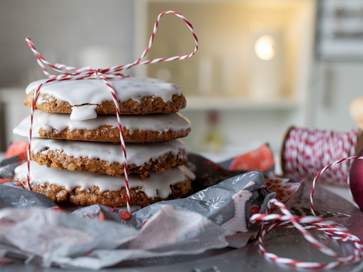 Frontalsicht: mehrere Nürnberger Lebkuchen liegen aufeinander und werden von einem weihnachtlich anmutendem Faden zusammengehalten. Die Anmutung ist weihnachtlich.