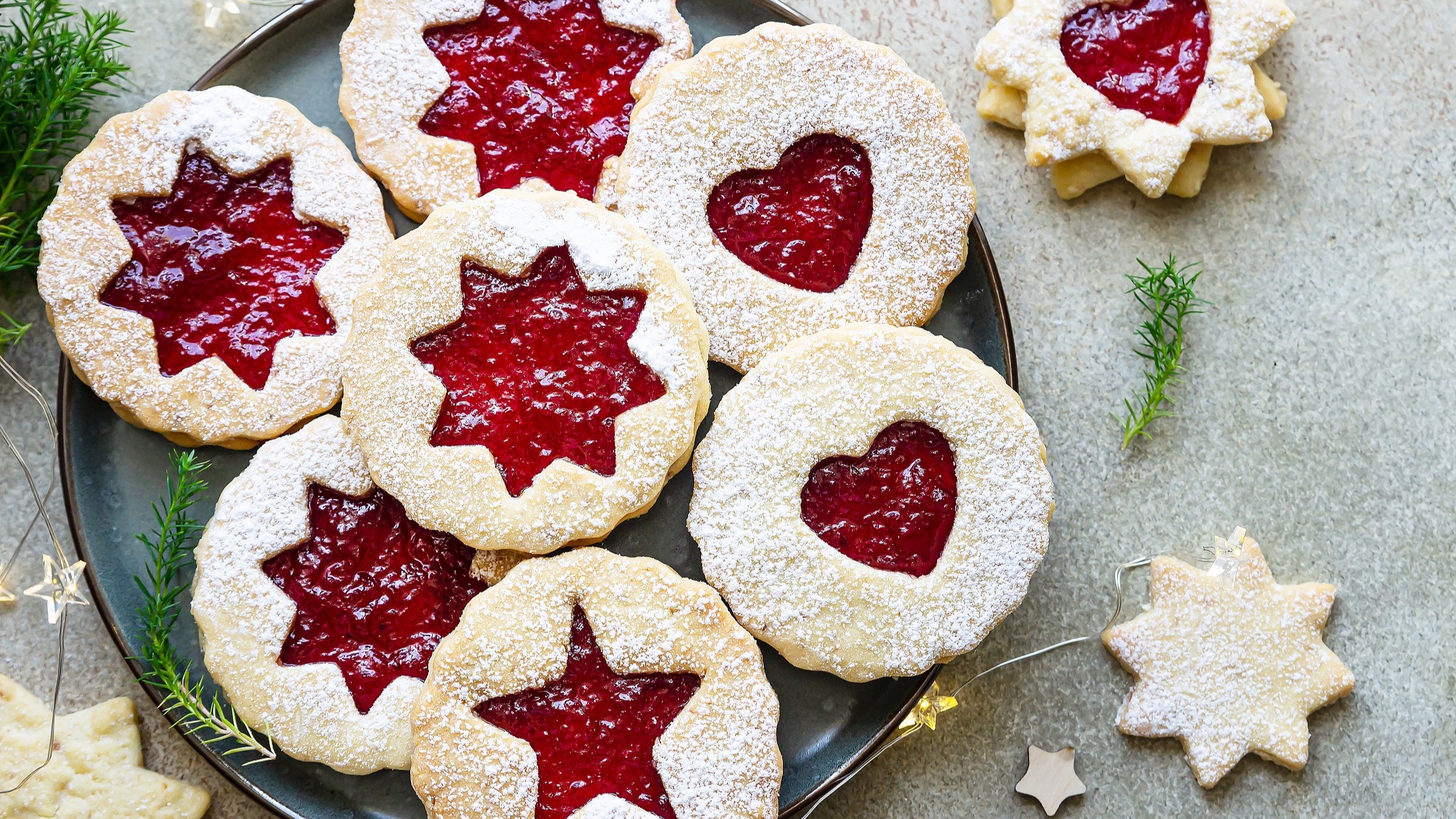 Draufsicht: Das Weihnachtsgebäck Spitzbuben liegt auf einem hellen Untergrund. Es sind 8 Spitzbuben.