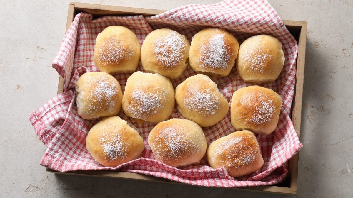 Elf Pizzabrötchen in einem Korb mit einem rot-karierten Tuch von oben fotografiert.