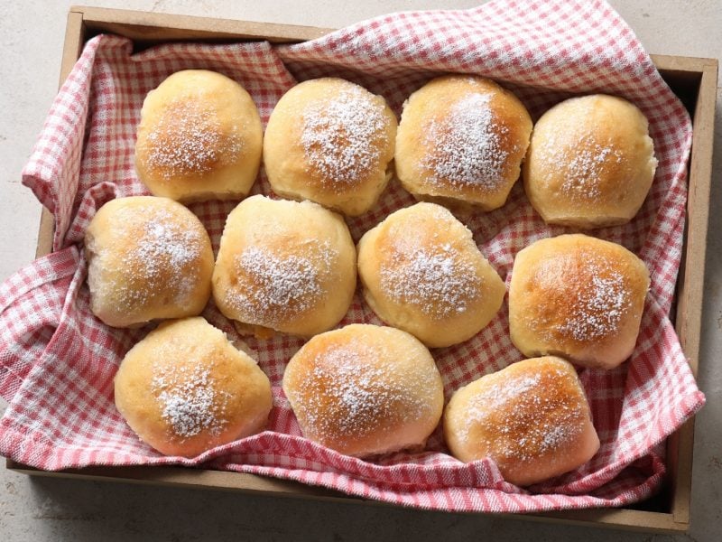 Elf Pizzabrötchen in einem Korb mit einem rot-karierten Tuch von oben fotografiert.