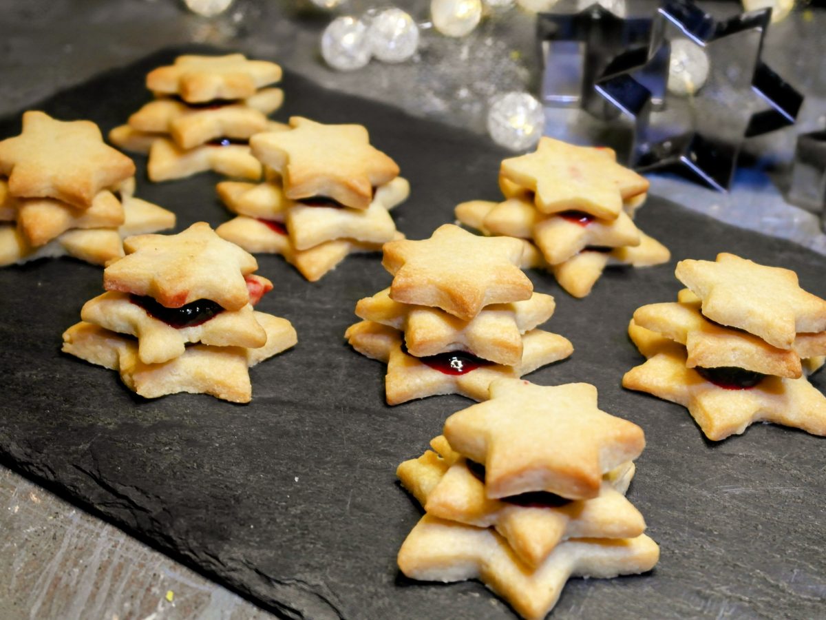 Mehrere Terrassen-Plätzchen auf einer schwarzen Schieferplatte von schräg oben fotografiert. Im Hintergrund weihnachtliche Dekoration.