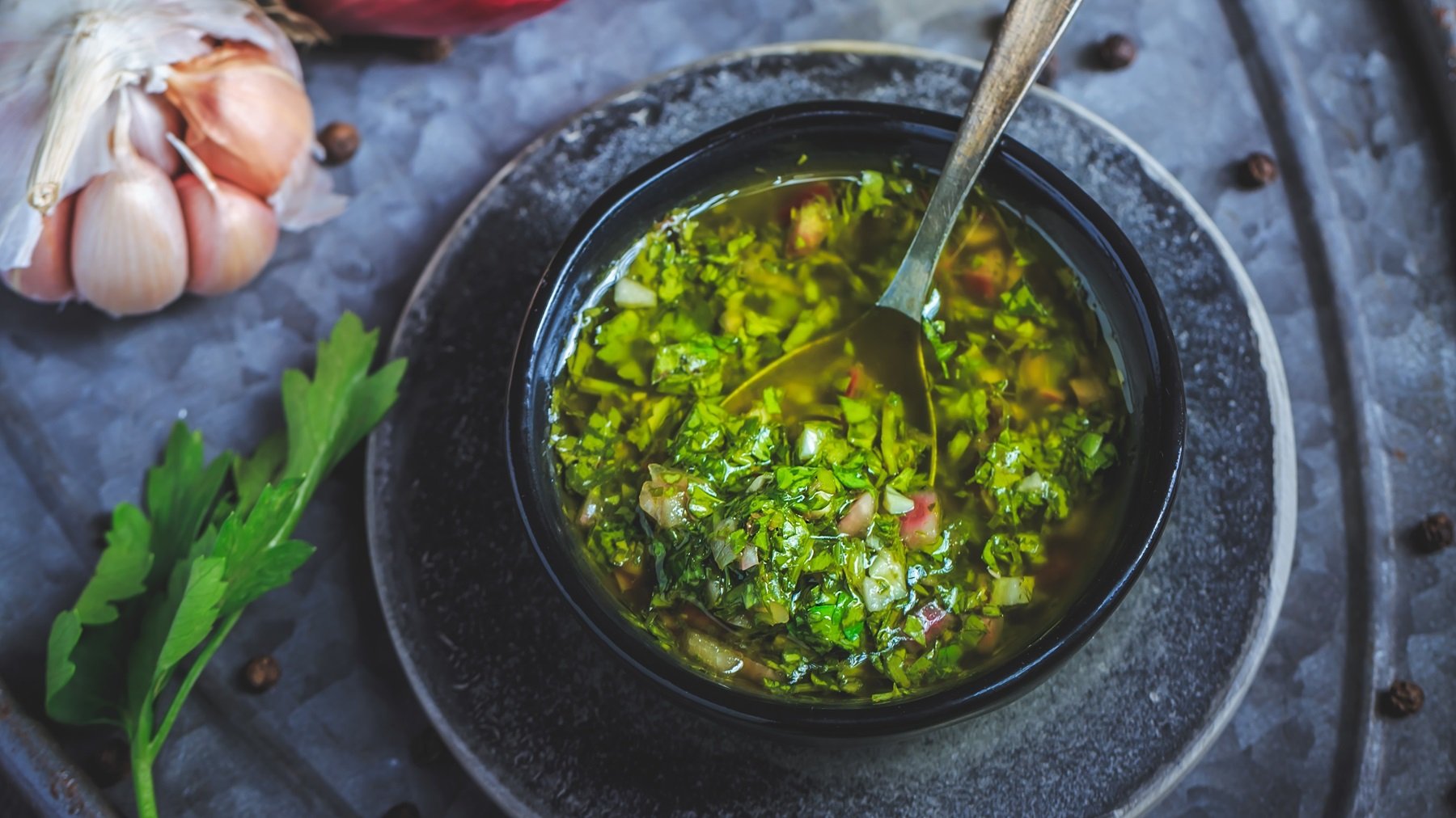 Ein graues Schälchen mit der grünen Kräutersauce auf einem grauen Tuch von oben fotografiert.