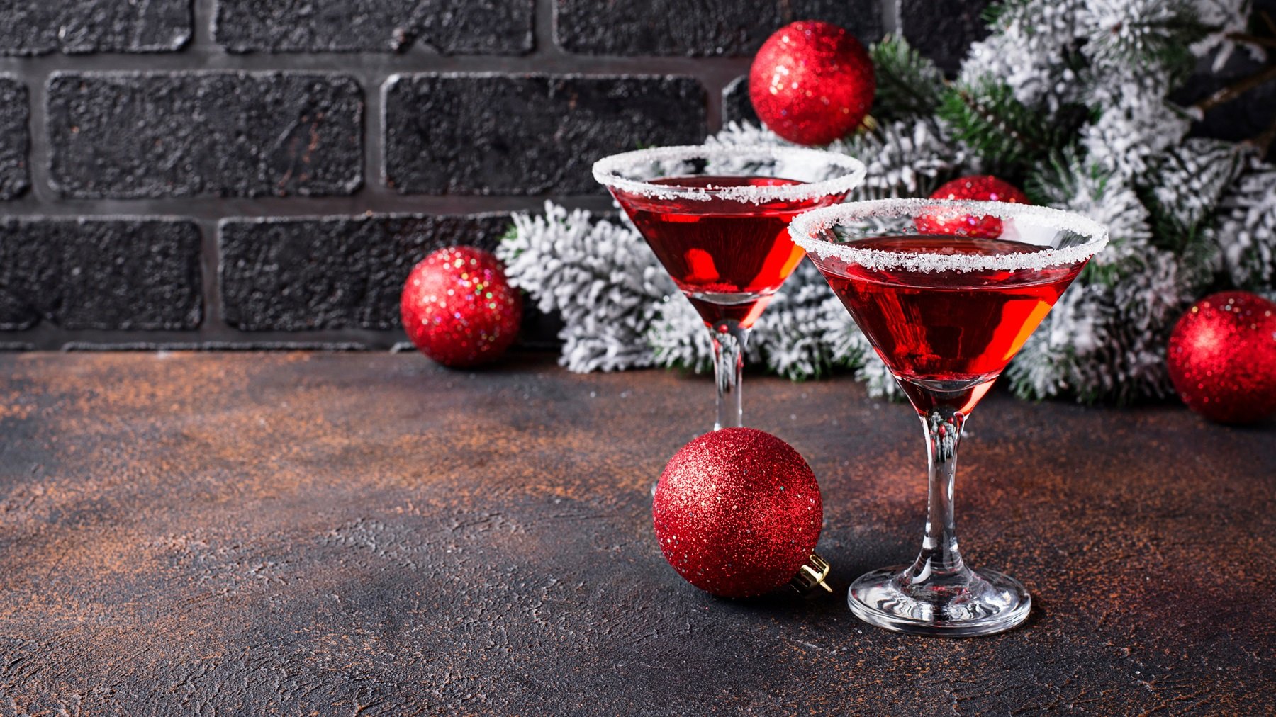 Zwei Martinigläser mit red Martini vor weihnachtlicher Dekoration.