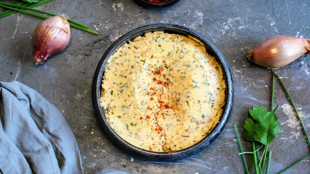 Eine graue Schale mit der Cowboy Butter auf einem grauen Steintisch, mit Kräutern und Schalotten direkt von oben fotografiert.