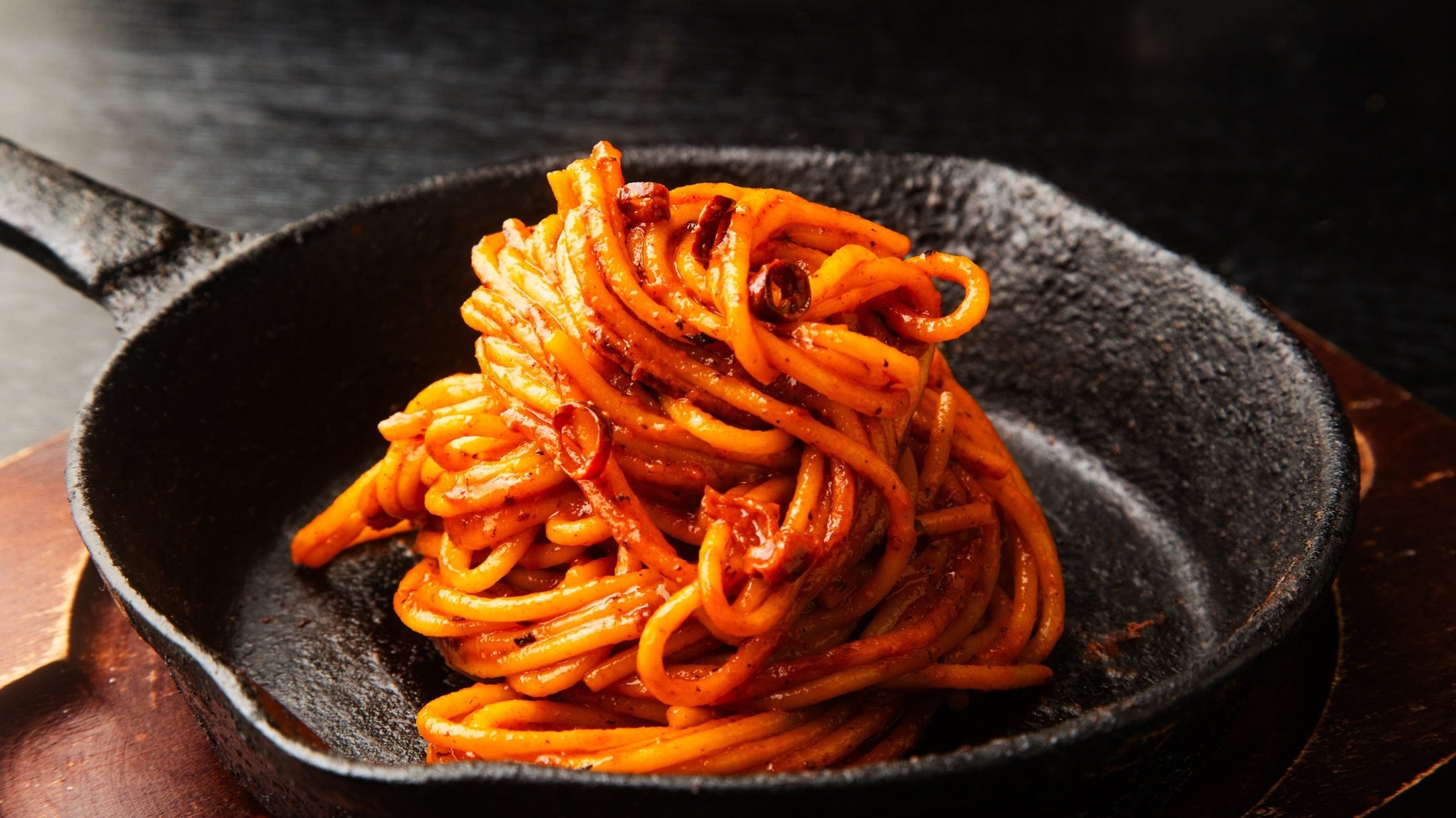 Frontal, schräg von oben: Eine schwarze gusseiseren Pfanne mit Spaghetti all'Assassina.